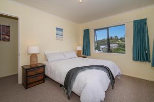 a bedroom with a large bed and a window at Hosts on the Coast Laze Away on Cook in Cooks Beach