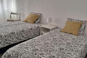 Un dormitorio con dos camas y una silla. en Casa Peixe Nazare, en Nazaré