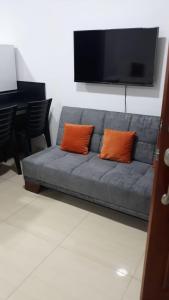 ein blaues Sofa mit zwei orangenen Kissen im Wohnzimmer in der Unterkunft DEPARTAMENTOS MARCECILIA DE 2 y 3 HABITACIONES EN EL CENTRO DE MANTA in Manta
