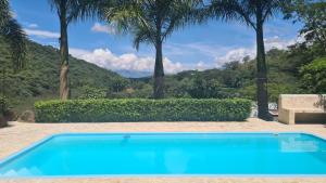 Ein blauer Swimmingpool mit Palmen im Hintergrund in der Unterkunft ENTREPALMAS in San Jerónimo
