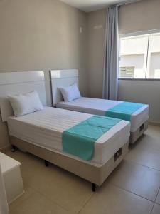 2 Einzelbetten in einem Zimmer mit Fenster in der Unterkunft Apartamento completo no centro de Tijucas 105 in Tijucas