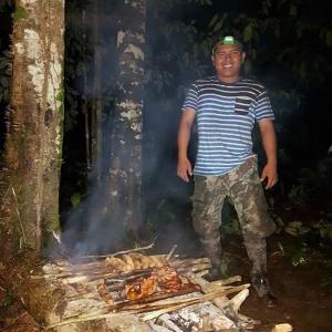 a man standing next to a fire in the woods at Amazon Jaguar Adventure & Lodge in Iquitos