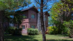 une maison en briques avec des arbres devant elle dans l'établissement Mirador del Indio, à Mar de las Pampas