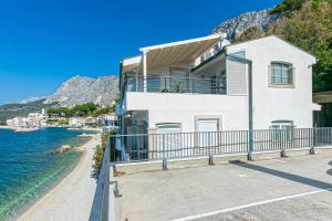 a white house with a balcony next to the water at Apartments by the sea Drasnice, Makarska - 6652 in Drasnice