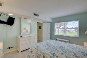 Un dormitorio con una cama y un televisor y una ventana. en El Matador 126 - Beautiful palm trees and ocean views! Close to all amenities of El Matador, en Fort Walton Beach
