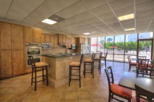 a kitchen with wooden cabinets and bar stools and tables at El Matador 165 - Beautiful unit with great view of the Gulf in Fort Walton Beach