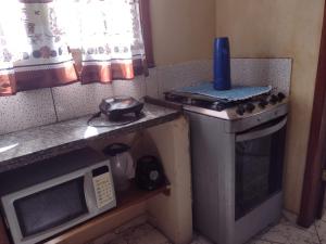 a small kitchen with a stove and a microwave at Sobrado aconchegante in Ilhéus