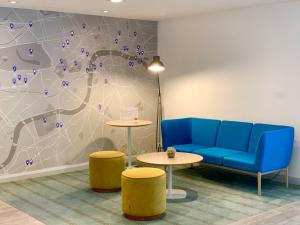a waiting room with a blue couch and two tables at Holiday Inn Express Earls Court, an IHG Hotel in London