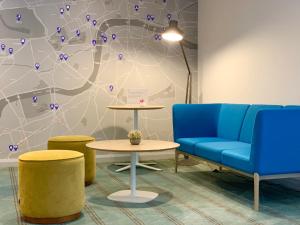 a waiting room with blue chairs and a table and a wall at Holiday Inn Express Earls Court, an IHG Hotel in London