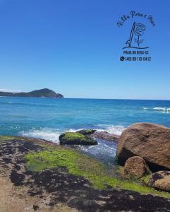 Una foto del océano con rocas en la playa en Villa Rosa e Mar - Praia do Rosa, en Imbituba
