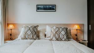 a bedroom with a white bed with two lamps at Vista del Piltri in El Bolsón