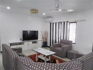 a living room with chairs and a table and a tv at Bula Holiday Inn in Nadi
