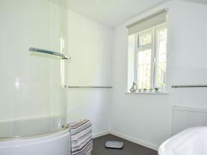 a white bathroom with a tub and a window at Ashgrove Cottage in Dudbridge