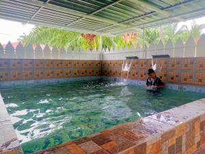 a child sitting in a pool of water at Villa Auliyya - MusleemHomestay in Kampong Sungai Leman