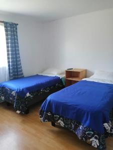 two beds in a room with blue sheets at Alojamiento Freire - Caviahue in Freire