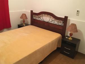 1 dormitorio con 1 cama y 2 mesitas de noche con lámparas en Cami III en Piriápolis