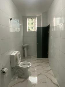 baño blanco con aseo y ventana en Hotel - Motel Story, en São Paulo