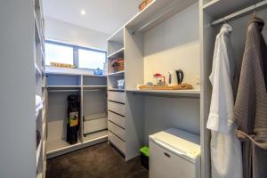 a walk in closet with blue walls and white cabinets at Seaside on Waiheke - Stay Waiheke in Blackpool