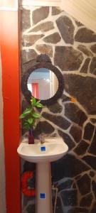 a bathroom with a sink and a stone wall at El Nido Cerro Azul in Cerro Azul