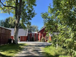 czerwona stodoła z drzewem na podjeździe w obiekcie Holiday home LIDKÖPING VIII w mieście Lidköping