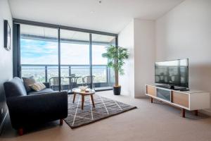 Lvl30 Garden/River views Balcony by Stylish Stays في بريزبين: غرفة معيشة مع أريكة وتلفزيون