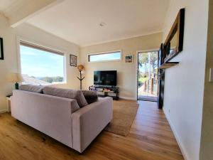 a living room with a couch and a tv at Daniu Ocean View Garden House in Merimbula