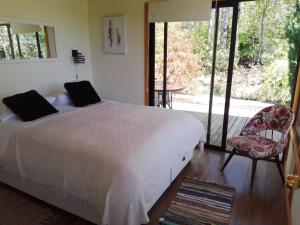 una camera con letto e sedia e un balcone di Cabañas Nordic lodge a Chillán Altre 37 foto