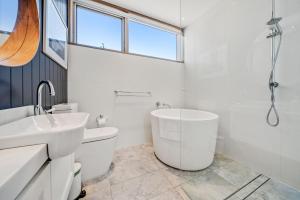 Baño blanco con bañera y lavamanos en 6A Alice Street Jindabyne, en Jindabyne