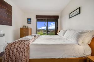 1 dormitorio con 1 cama blanca grande y ventana en Ned Kellys Retreat Sophisticated style with modern convenience and magical outlook, en Jindabyne