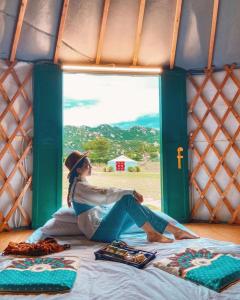 une femme assise sur un lit dans une tente dans l'établissement Tanyoli Resort, à Phan Rang