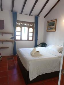 a bedroom with a large white bed with a window at Hostal Home Sant Angelo in Villa de Leyva