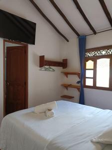 1 dormitorio con cama blanca y ventana en Hostal Home Sant Angelo en Villa de Leyva