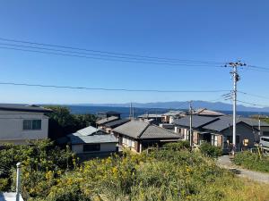 a row of houses on a hill with mountains in the background at ゲストハウスKOIZUMI in Oshima