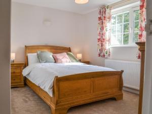 a bedroom with a wooden bed and a window at Ripple Farm Cottage in Great Mongeham