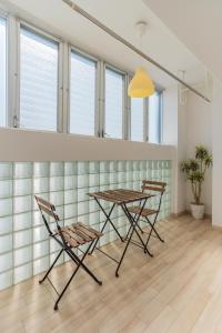 einen Tisch und Stühle in einem Zimmer mit Fenstern in der Unterkunft Universal Bay Condominium in Osaka