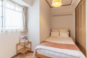um pequeno quarto com uma cama e uma janela em Universal Bay Condominium em Osaka