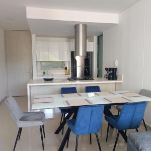 a kitchen with a dining table and blue chairs at Samaria - Apartamento en Club de Playa, Santa Marta in Santa Marta