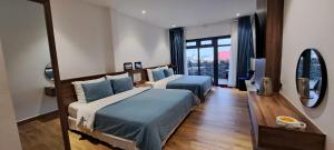 een slaapkamer met twee bedden en een groot raam bij Ánh Dương House in Da Lat