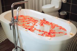 a bath tub filled with red flowers in a bathroom at Danaciti Hotel in Danang