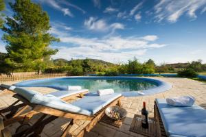 una piscina con 2 tumbonas y una botella de vino en Casa Carla en Ibiza