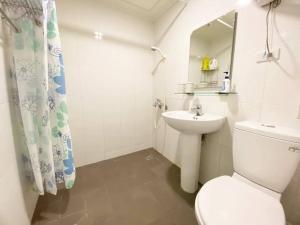 a white bathroom with a toilet and a sink at Tainan Homestay in Tainan