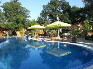ein großer blauer Swimmingpool mit Sonnenschirmen in einem Garten in der Unterkunft Туристически комплекс"Странджа" in Sredets