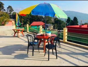 a table and chairs with an umbrella on a roof at Hidden Gem Residency in Kalimpong