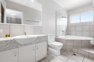 a white bathroom with a sink and a toilet at 7 Riverside in Noosaville +3 photos