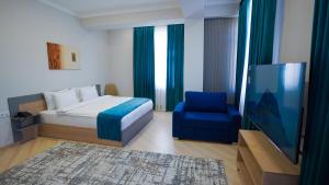 Un dormitorio con una cama y una silla azul. en Almalyk Plaza Hotel, en Olmaliq