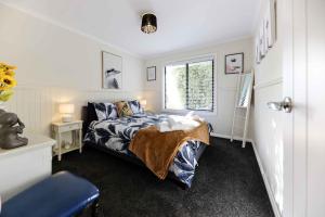 Schlafzimmer mit einem Bett und einem Fenster in der Unterkunft Hidden Gem ~ Luxury Cottage near Lake Daylesford in Daylesford