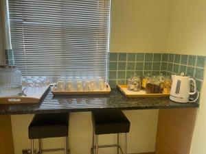 a kitchen counter with two bar stools and glasses on it at Shared house on Southmead in Bristol