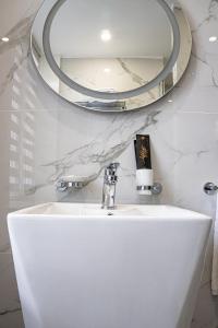 La salle de bains est pourvue d'un lavabo blanc et d'un miroir. dans l'établissement Resident Hotel Kazybek Bi, à Almaty