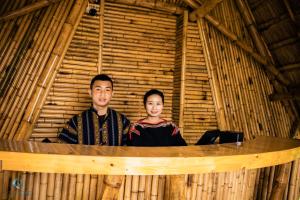 un homme et une femme debout dans une cabane en bambou dans l'établissement Lang's Pá Mé - Homestay - Bungalow - Camping Krông Pắk, Buôn Mê Thuột, Đắk Lắk, Việt Nam, à Dak Lak