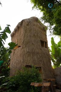 a thatched building with a thatched roof at Lang's Pá Mé - Homestay - Bungalow - Camping Krông Pắk, Buôn Mê Thuột, Đắk Lắk, Việt Nam in Dak Lak